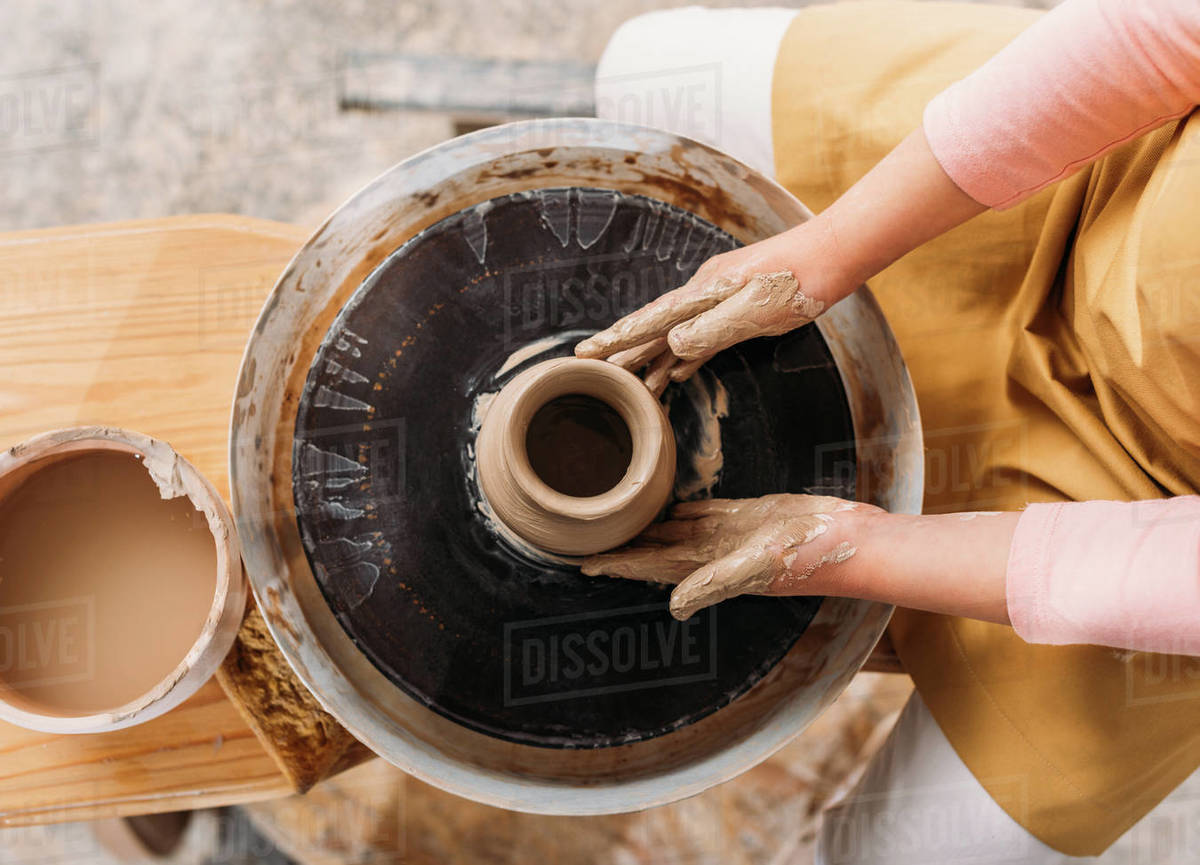 Cropped view of child making ceramic pot with clay on pottery wheel