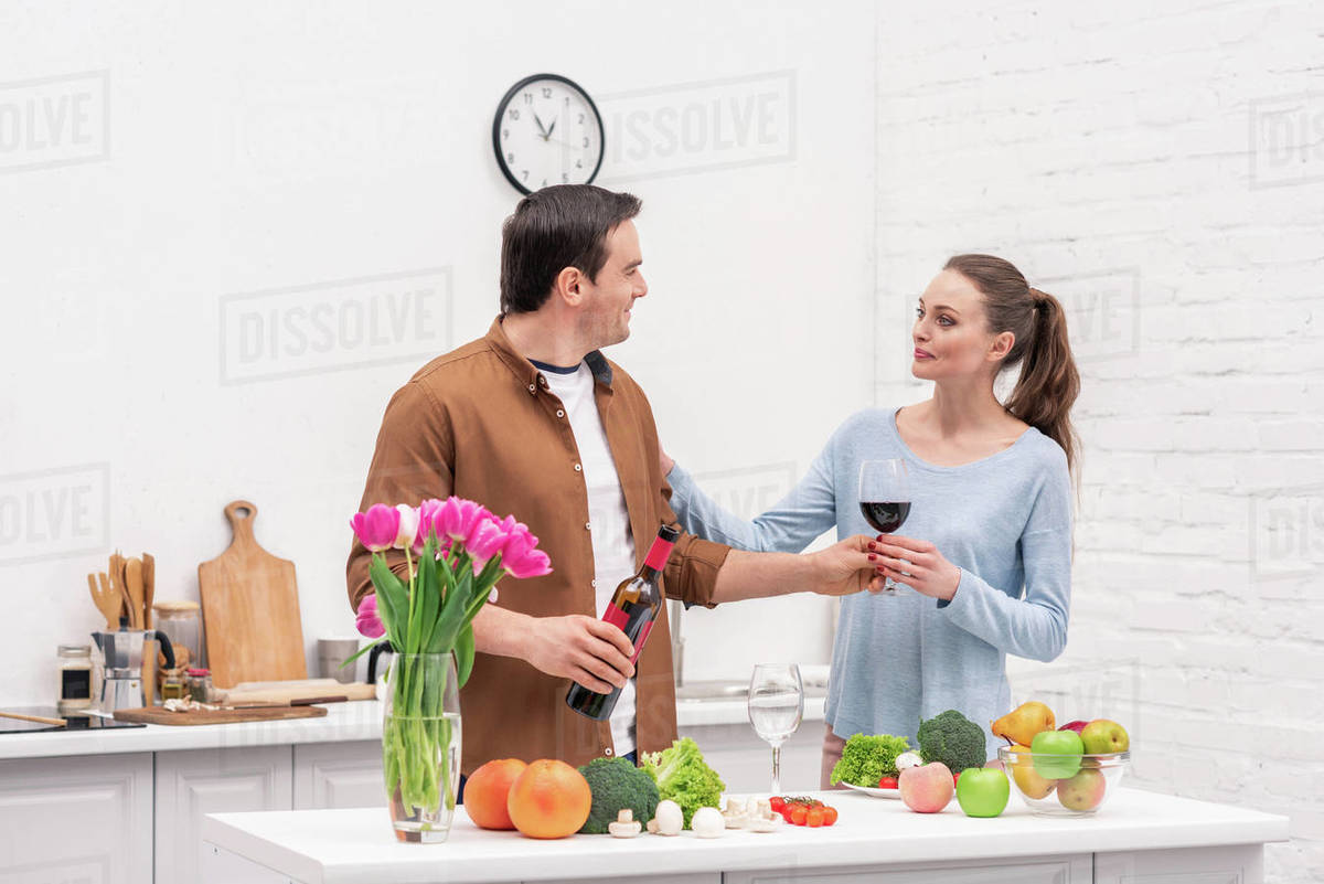 Beautiful adult couple with red wine cooking together at kitchen
