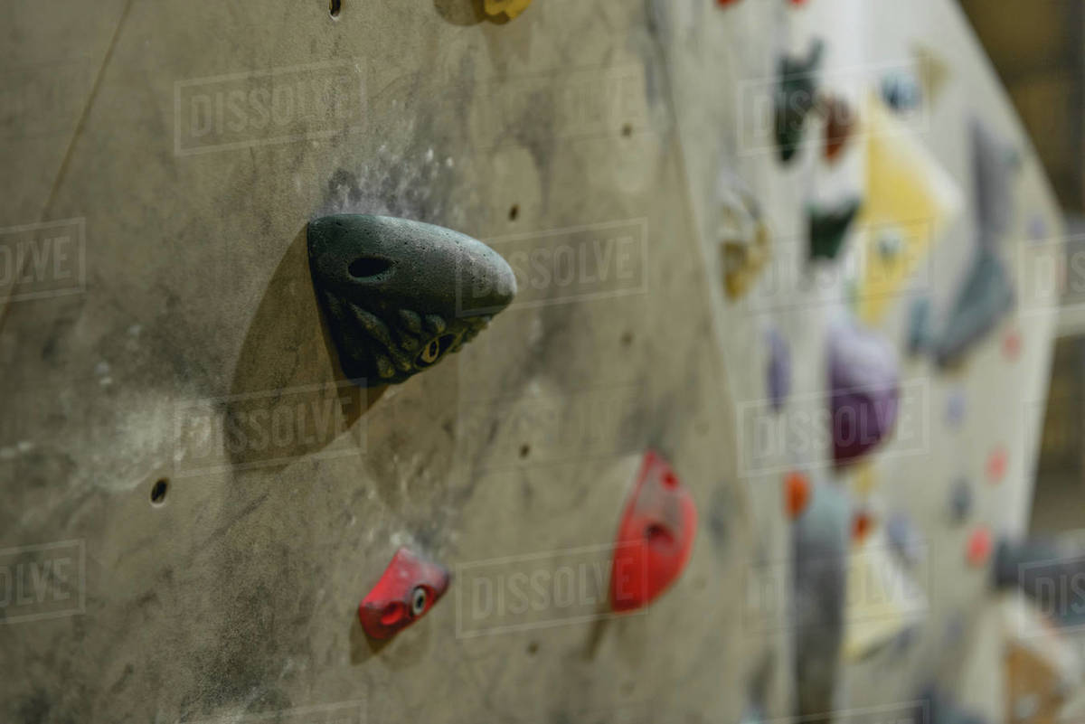 Closeup shot of grips for hands on a climbing wall at gym - Stock Photo