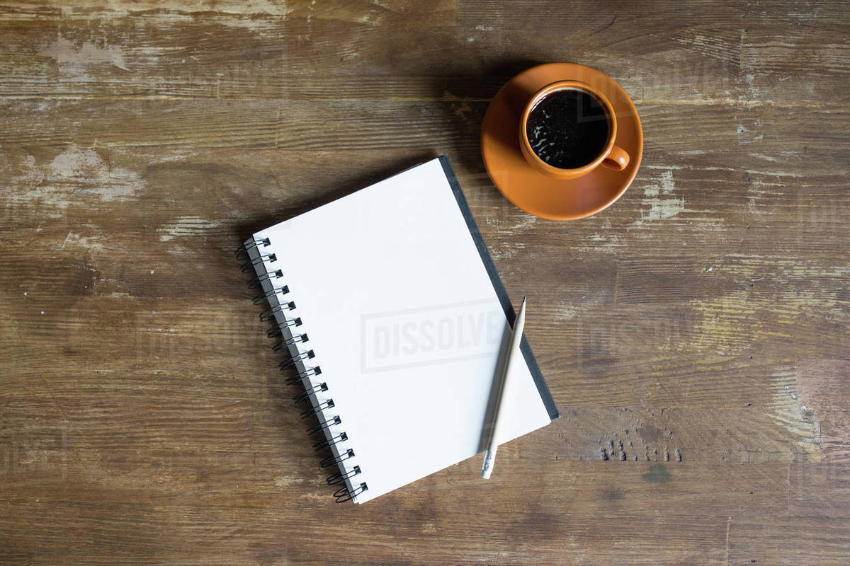 Top view of notepad with pencil and coffee cup on wooden tabletop ...
