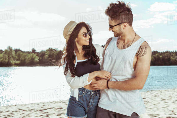 Man and woman hugging each other while walking together on beach on ...
