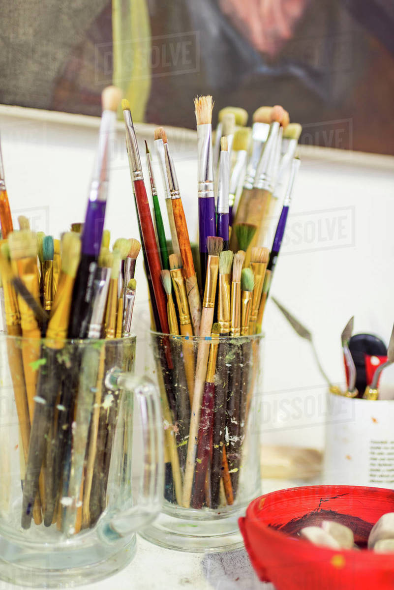 Painting brushes in glasses on table in Stock Photo Dissolve