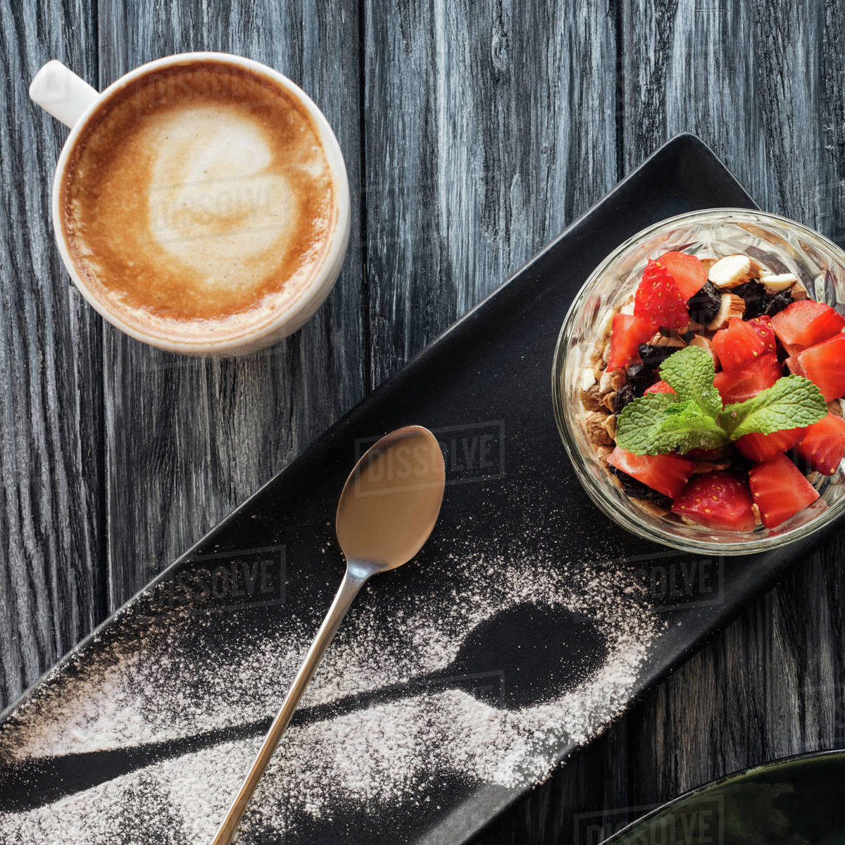 Top view of healthy fruity dessert, spoon and cup of coffee on wooden