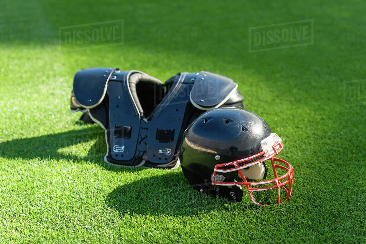 American football helmet with chest protection lying on green grass