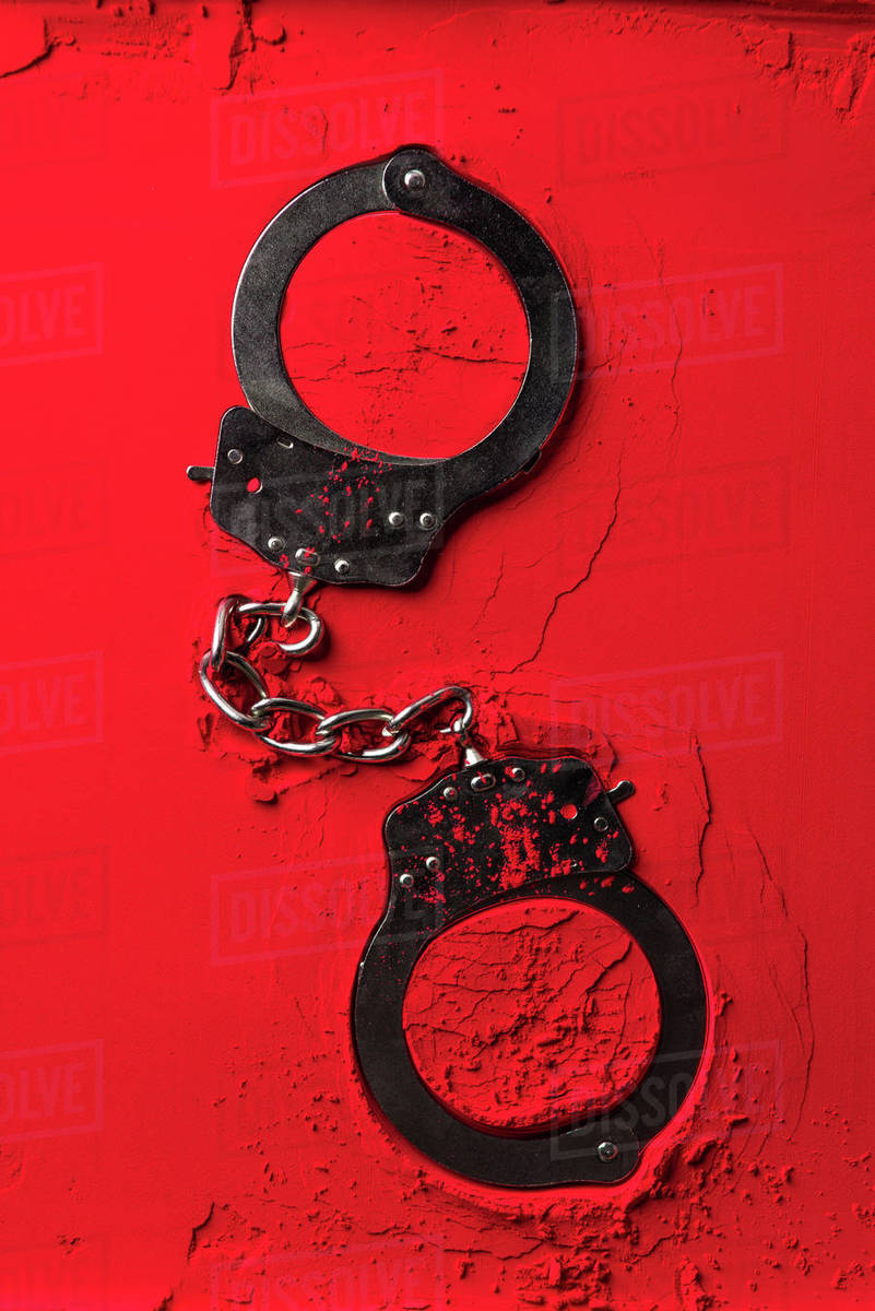 top view of black handcuffs red powder Stock Photo Dissolve