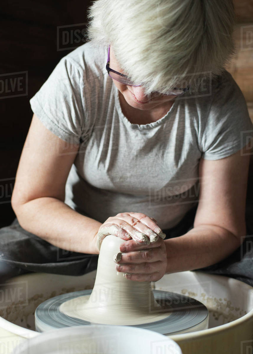 Female potter molding wet clay on a pottery wheel in her