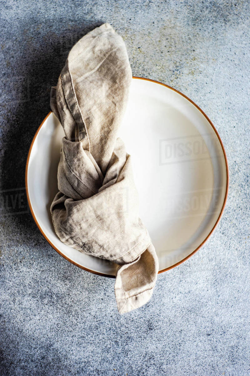 Overhead view of a rustic napkin tied in a knot on a ceramic bowl Stock Photo Dissolve