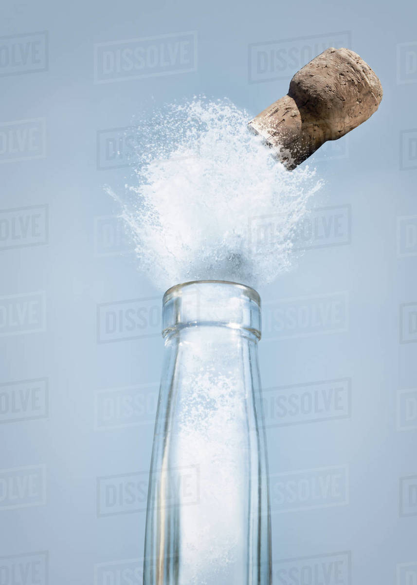 Close-up of liquid and a cork exploding out of a long neck bottle