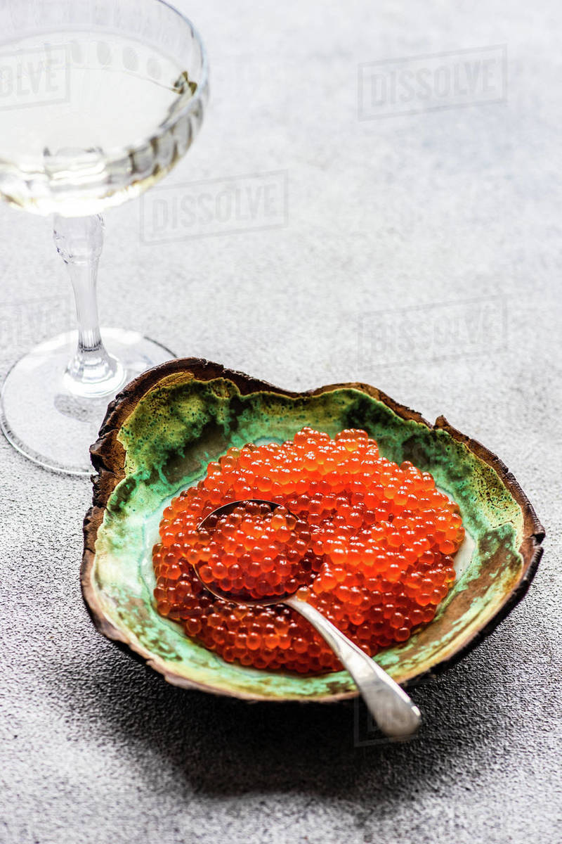 Close-up of a bowl of red trout caviar and a glass of white wine ...