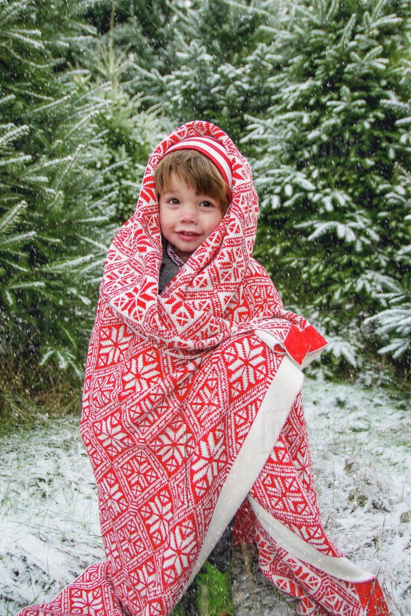 Boy standing outside in snow, wrapped in blanket Stock Photo Dissolve