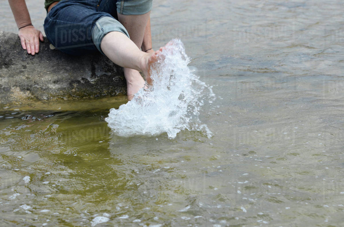 Woman splashing feet in sea - Royalty-free Stock Photo | Dissolve