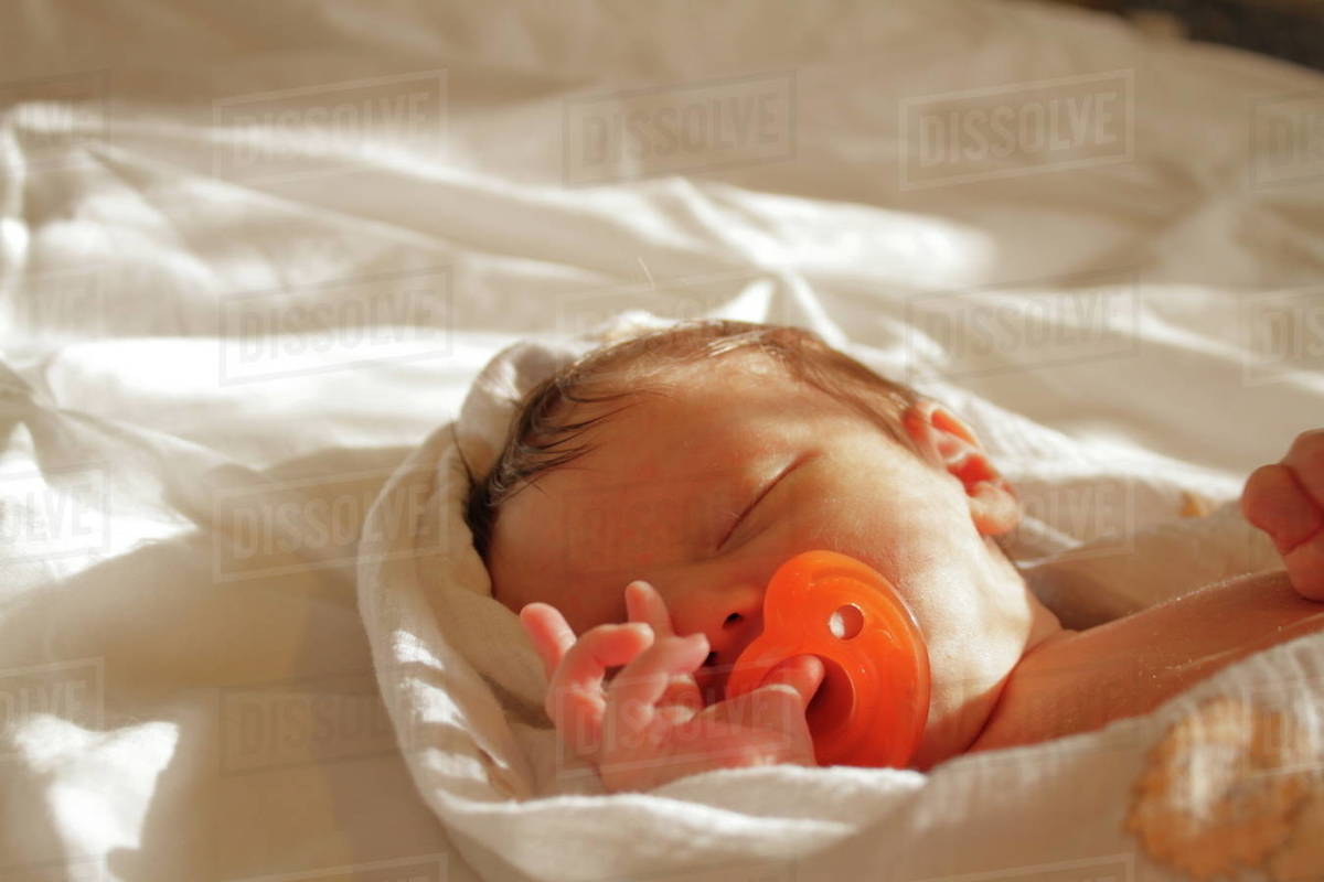 Newborn baby boy sleeping in bed with pacifier Stock Photo Dissolve