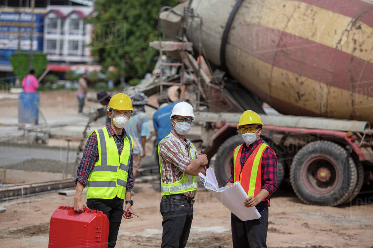 Three engineers on a construction site, Thailand Stock Photo Dissolve