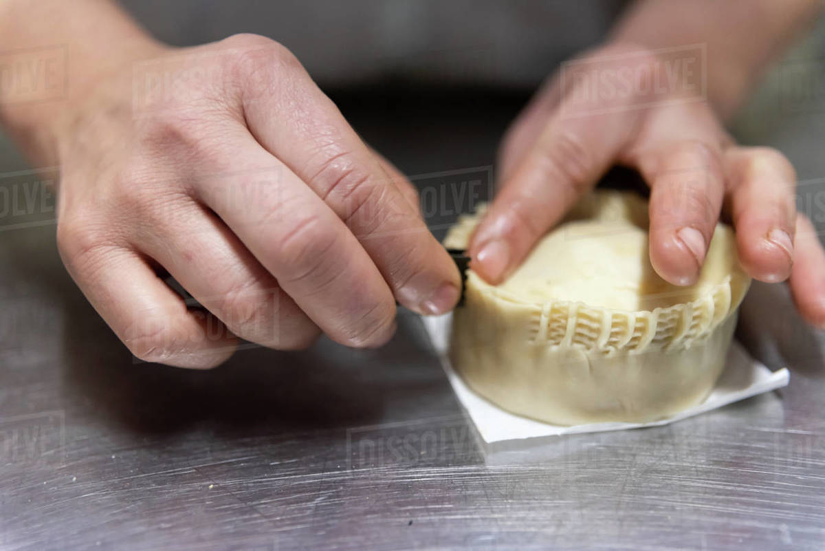 Closeup anonymous person pinching pie crust on metal table in modern
