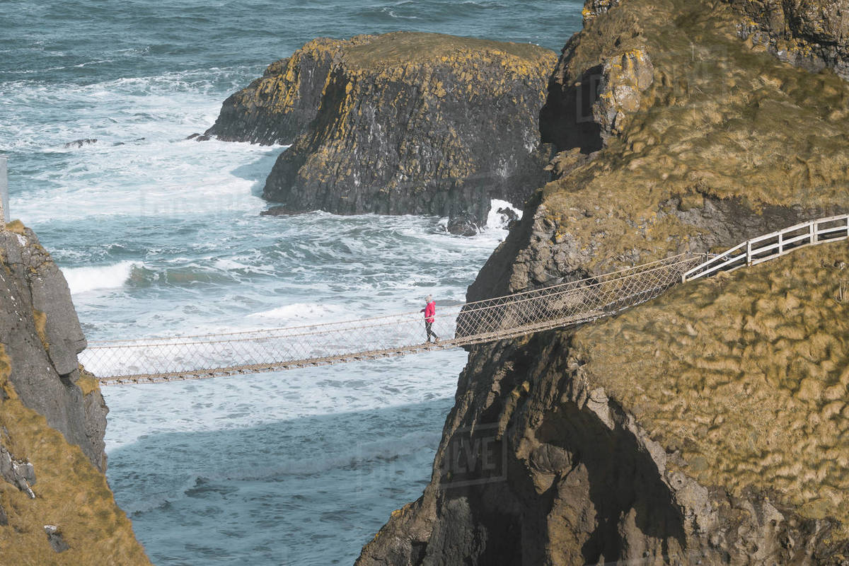From above side view of traveler passing over Carric a Rede rope bridge