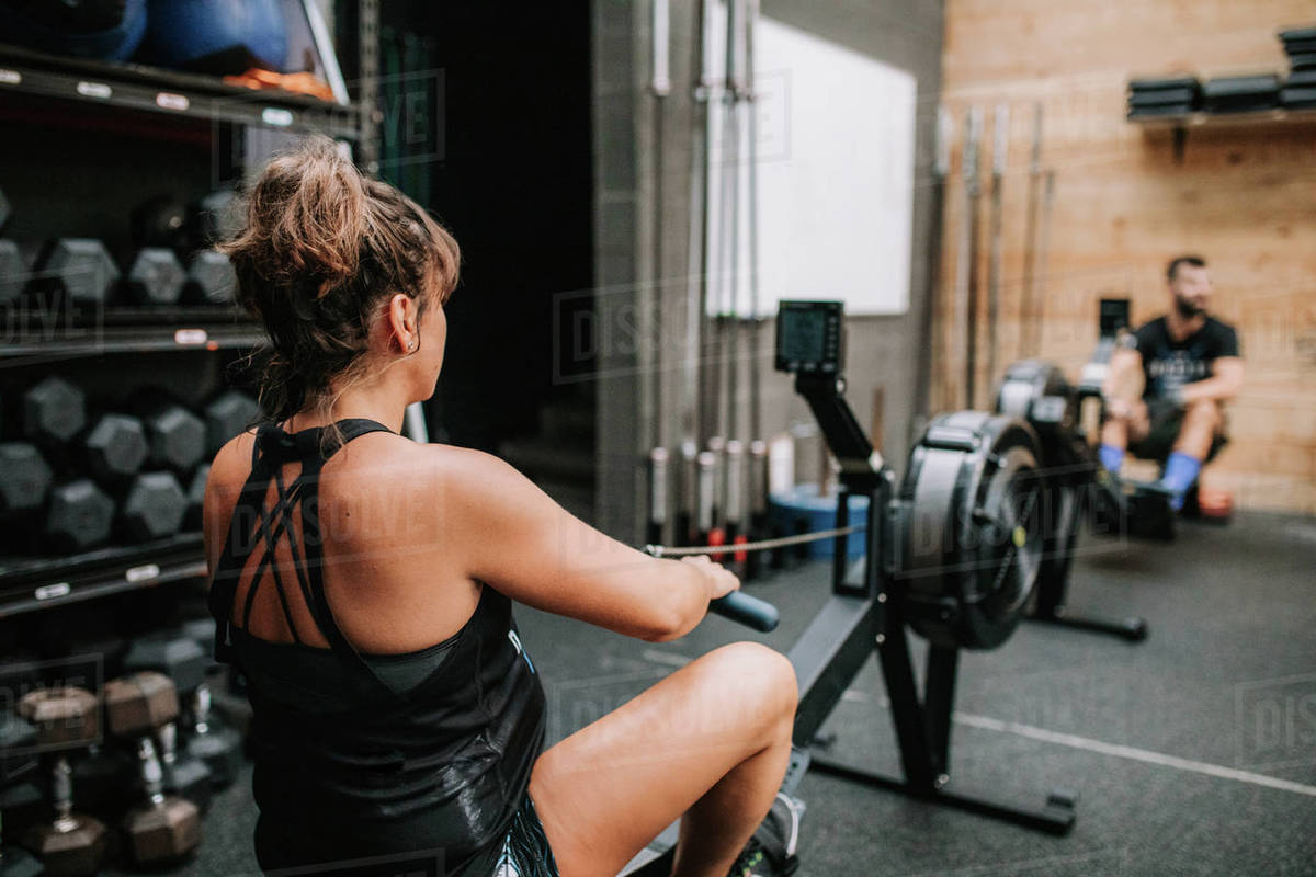 Back view of unrecognizable pregnant female athlete training on rowing