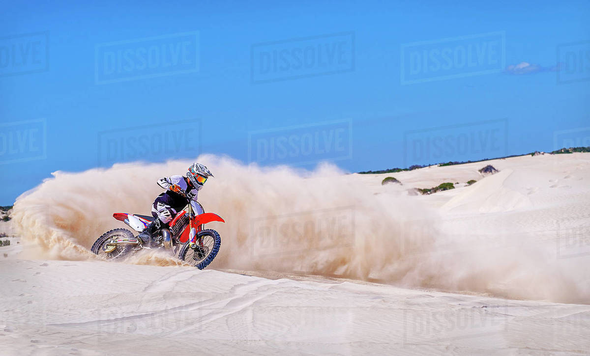 Trial bike rider kicking up sand at the sand dunes of Lancelin, Western