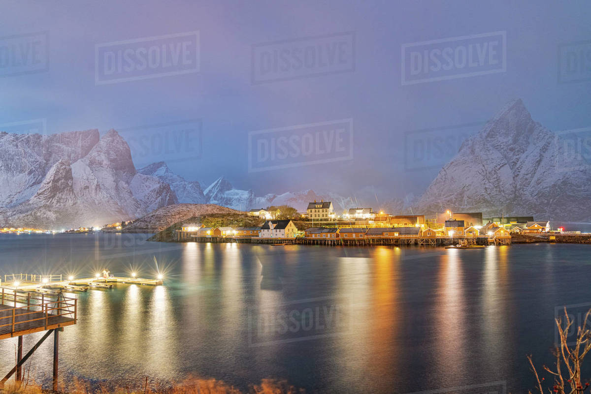 Illuminated Rorbu and houses in night fog during the cold winter, Sakrisoy, Reine, Nordland