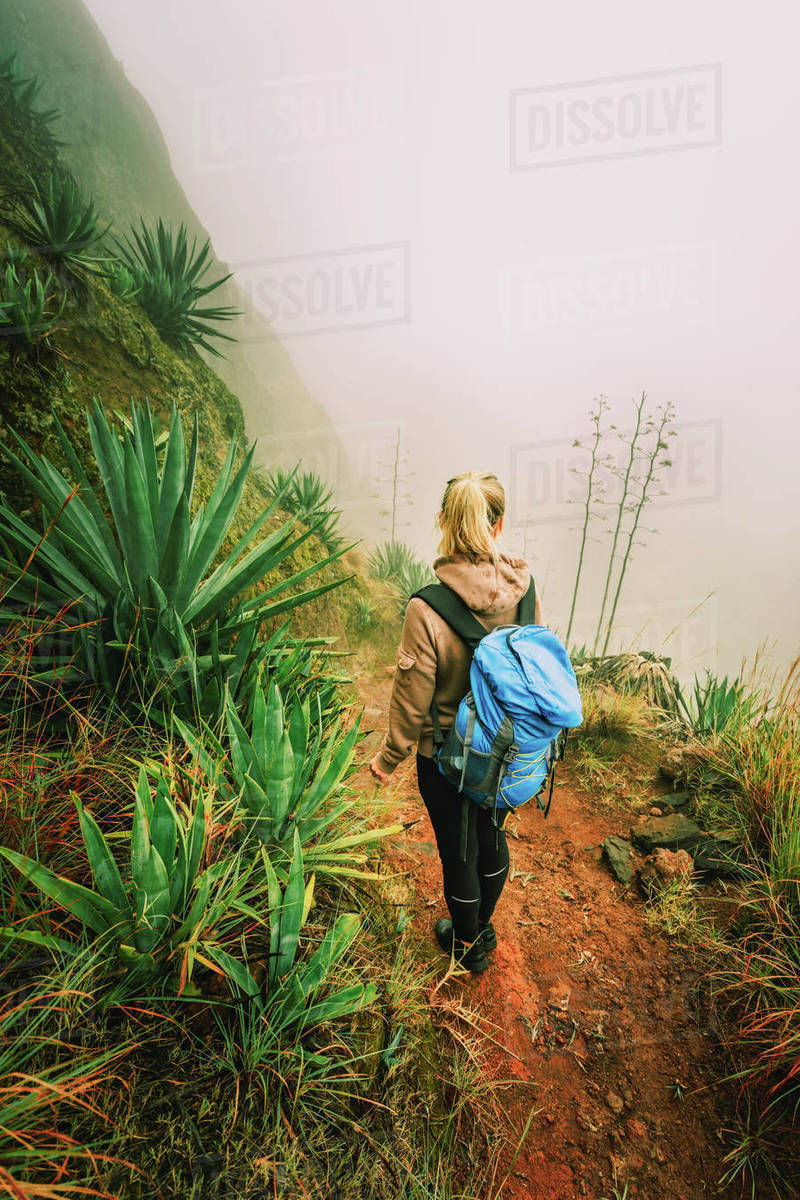 Santo Antao, Cape Verde. Women with backpack hike down the steep slope of the rock in the foggy mountains. Royalty-free stock photo