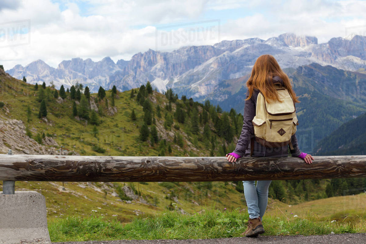 girl hiker sitting and looking at the snowed mountains. Dolomites, Italy. Royalty-free stock photo