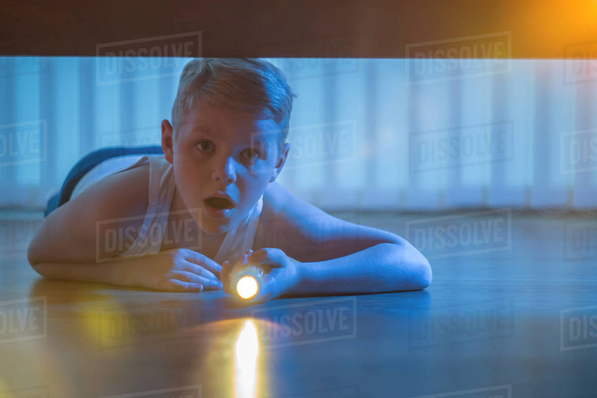 The boy lay on the floor with a flashlight. night time Stock Photo