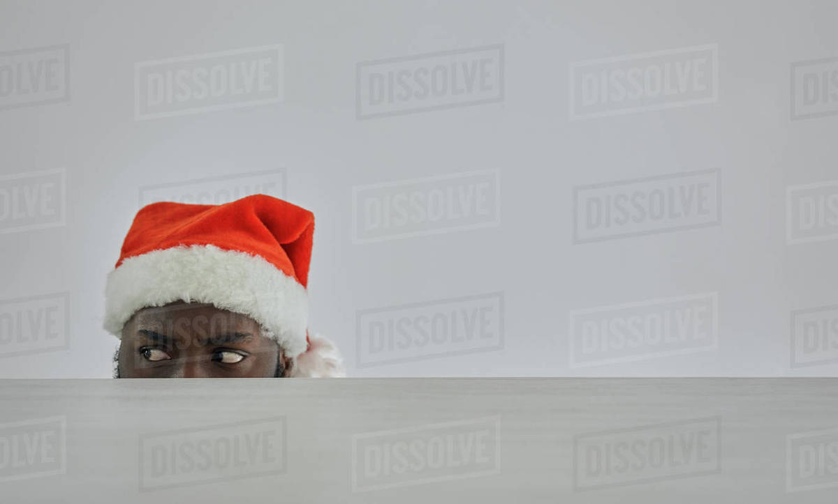 The african man in the santa hat watching from the table Royalty-free stock photo