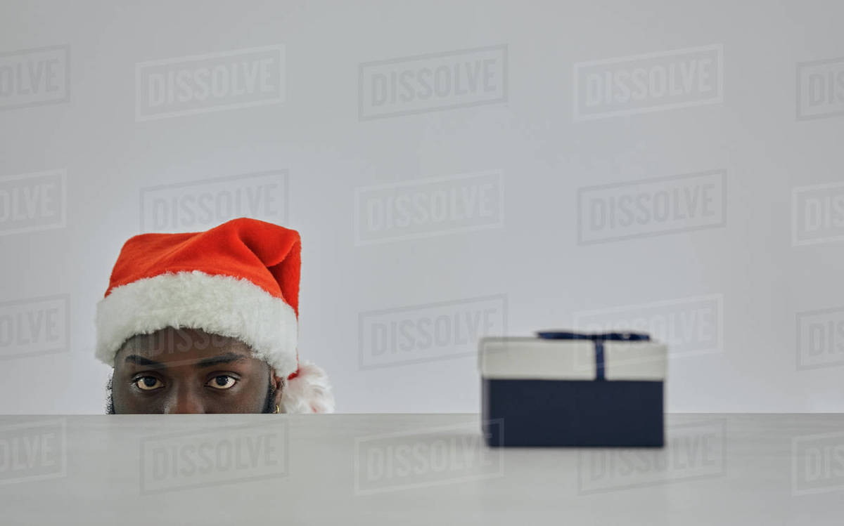 The african man in the santa hat watching from the table with a gift Royalty-free stock photo