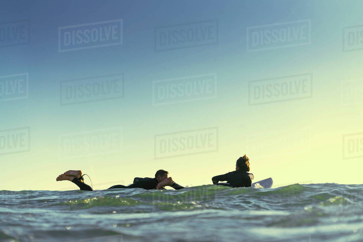 Surfing couple paddling surfboards at sea, Newport Beach, California, USA Stock Photo Dissolve