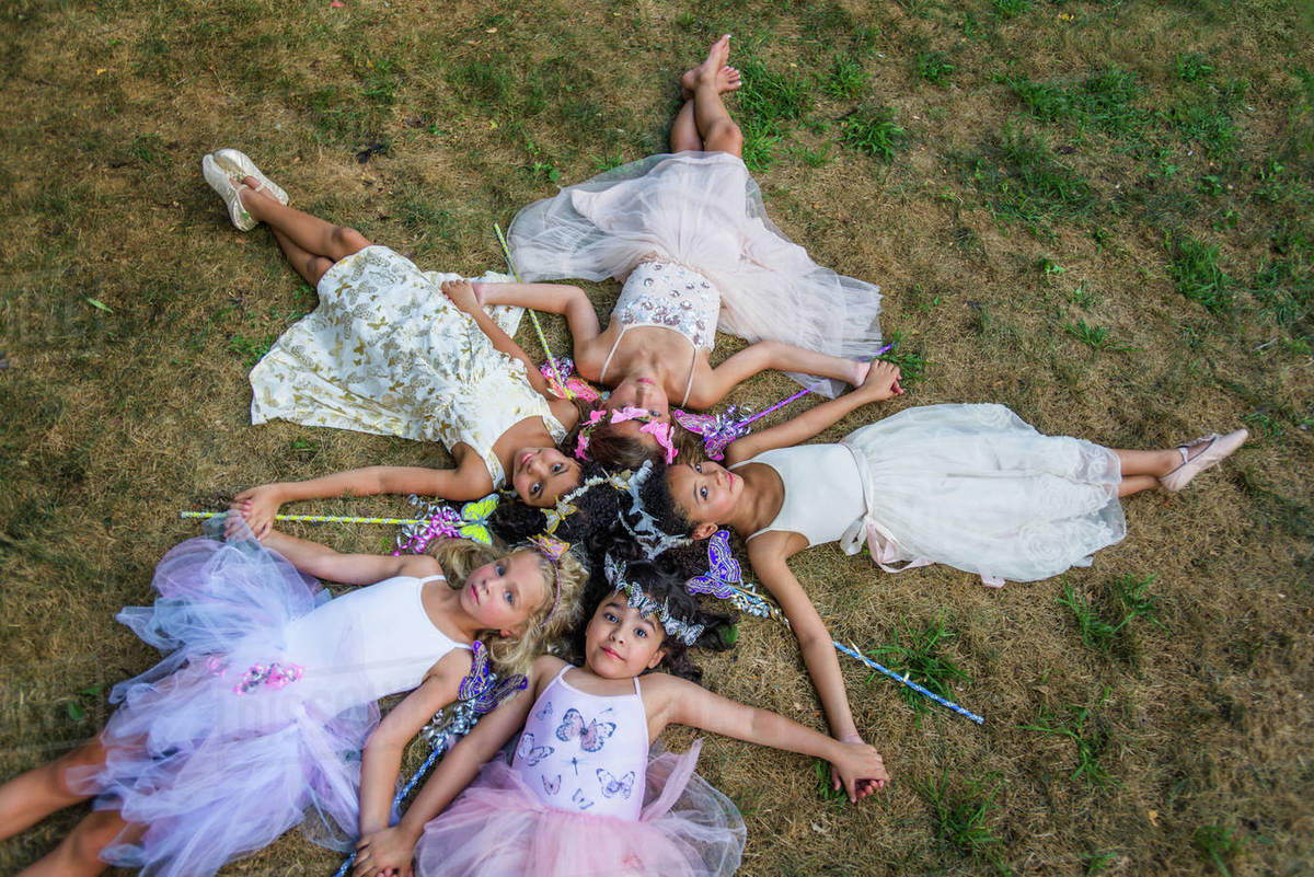 Group of young girls dressed as fairies, lying in circle, heads together Royalty-free stock photo