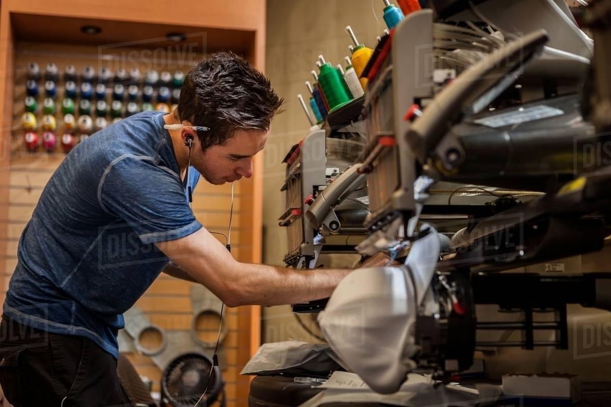 Worker preparing embroidery machine in tshirt printing