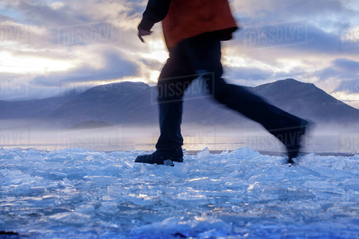 Hiker walking on ice in rural landscape Stock Photo Dissolve