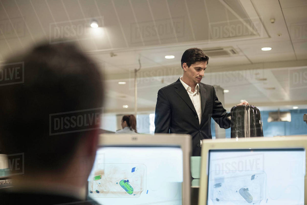 Security guard checking luggage on monitor in airport Stock Photo