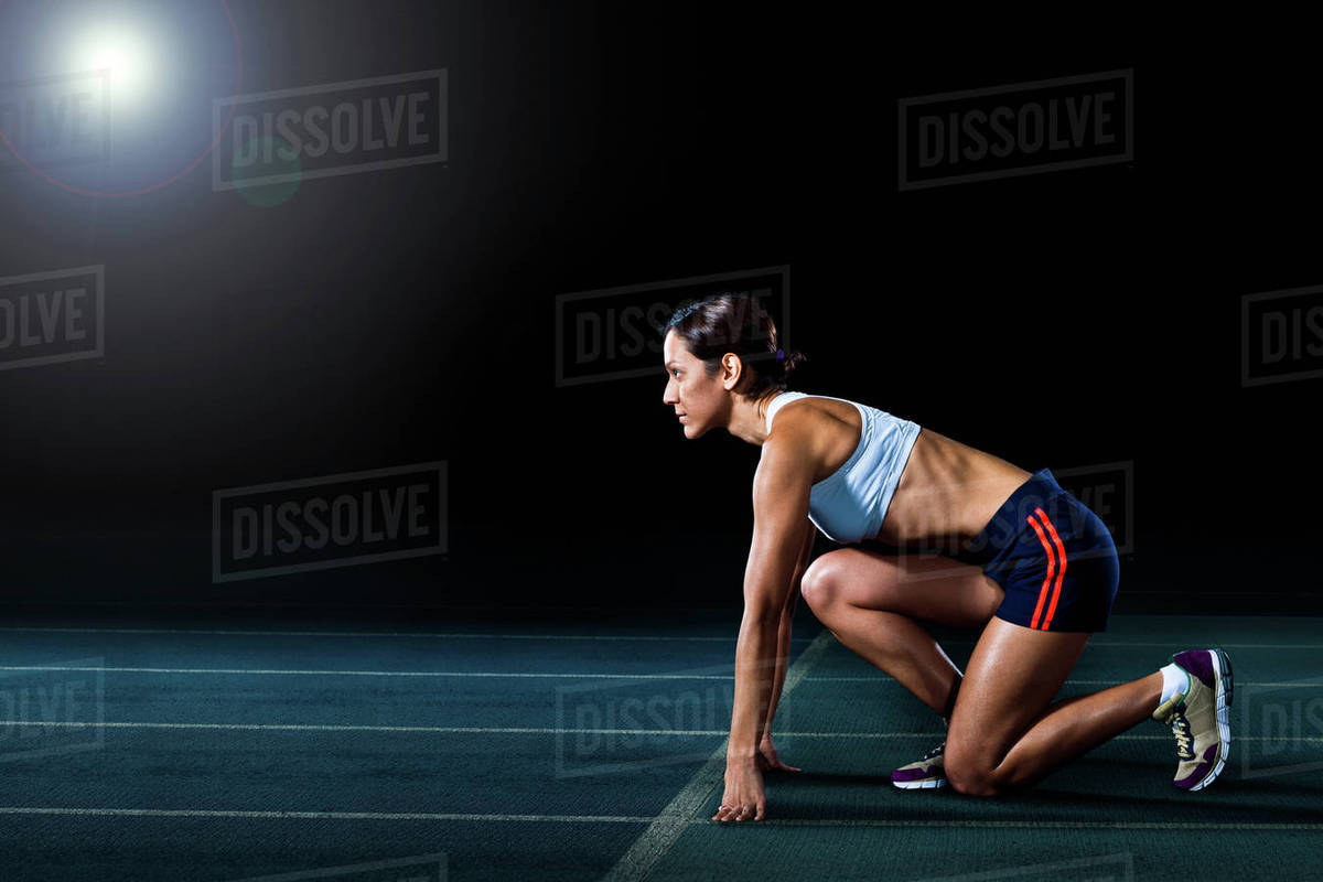 Female athlete in starting position on running track Stock Photo