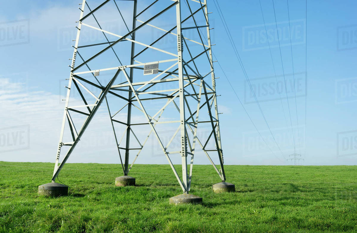 Electrical towers and power lines over green field Stock Photo Dissolve