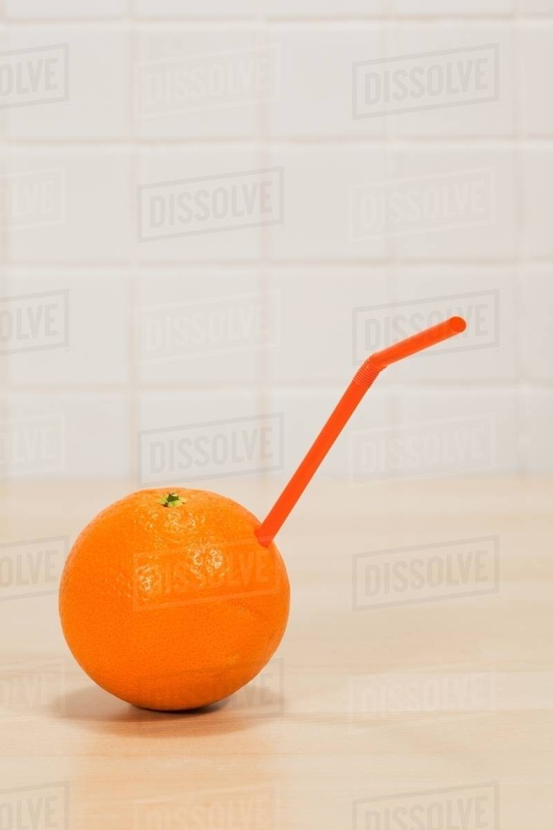 Orange with drinking straw sticking out Stock Photo Dissolve