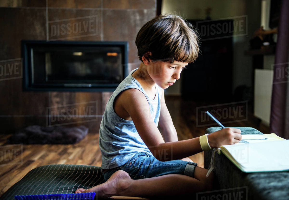 boy kneeling on floor drawing in workbook stock photo dissolve workbook stock