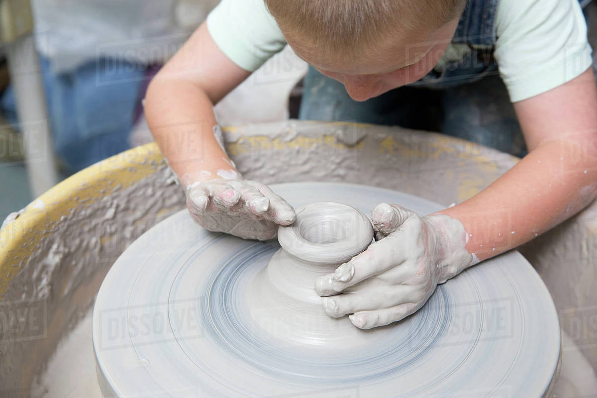 Boy shaping clay on potter's wheel Stock Photo Dissolve