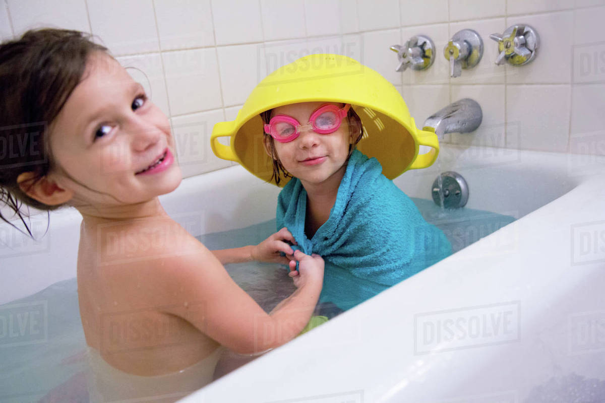 Girl having fun dressing up sister in bathtub Stock Photo Dissolve