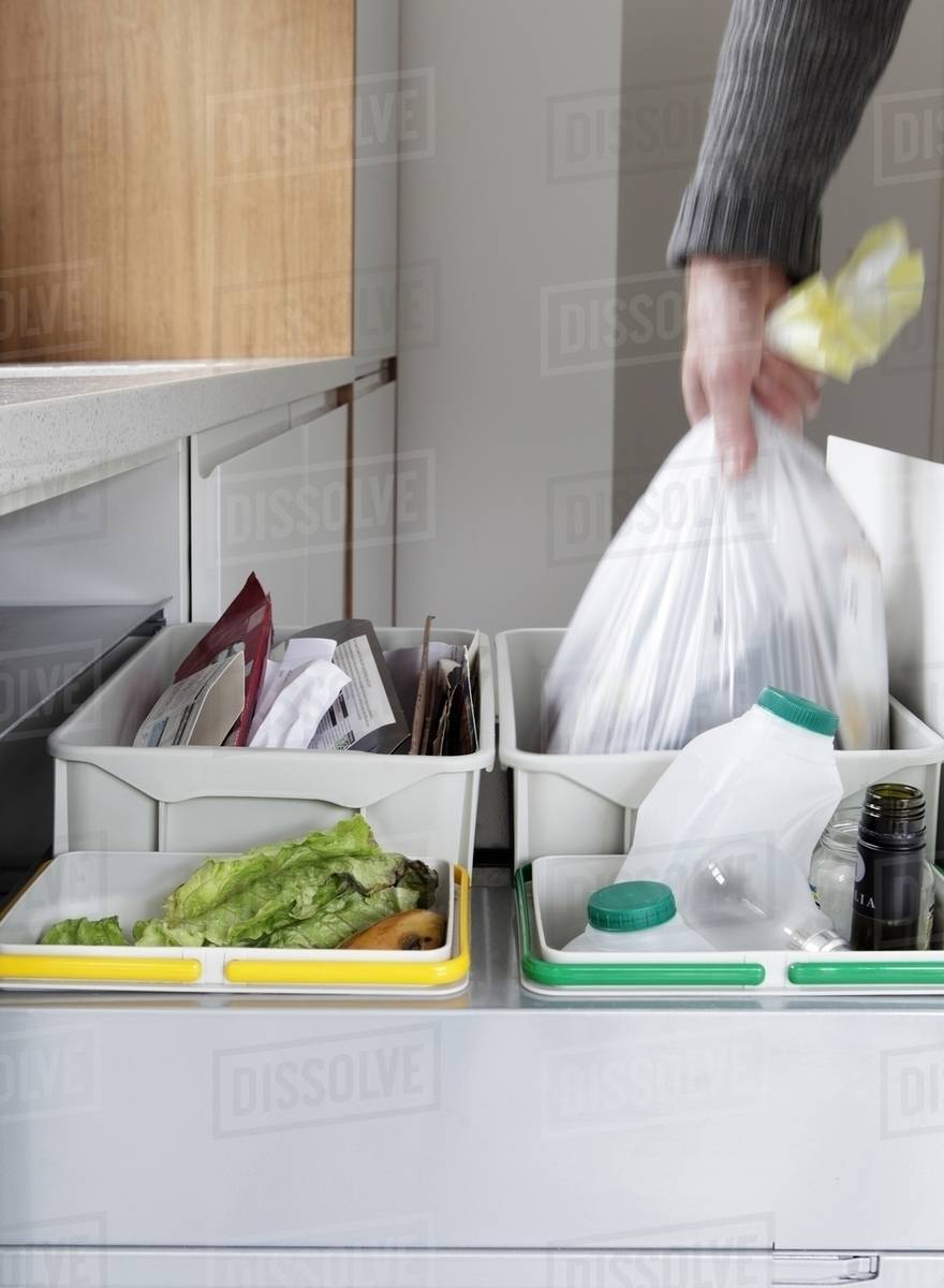 Person removing rubbish bag from waste and recycling drawer Stock