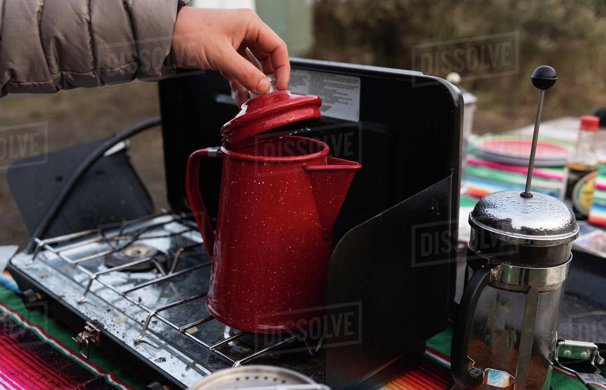 Camper checking kettle on camping stove Stock Photo Dissolve