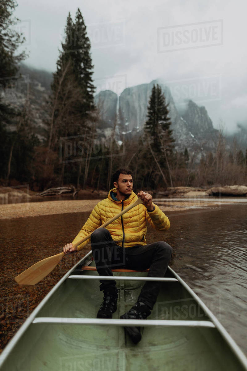 Young male canoeist rowing canoe on river, Yosemite Village, California