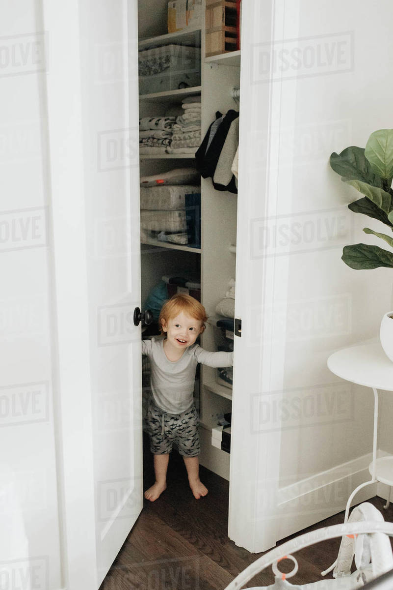 Toddler opening door from inside of storeroom Stock Photo Dissolve