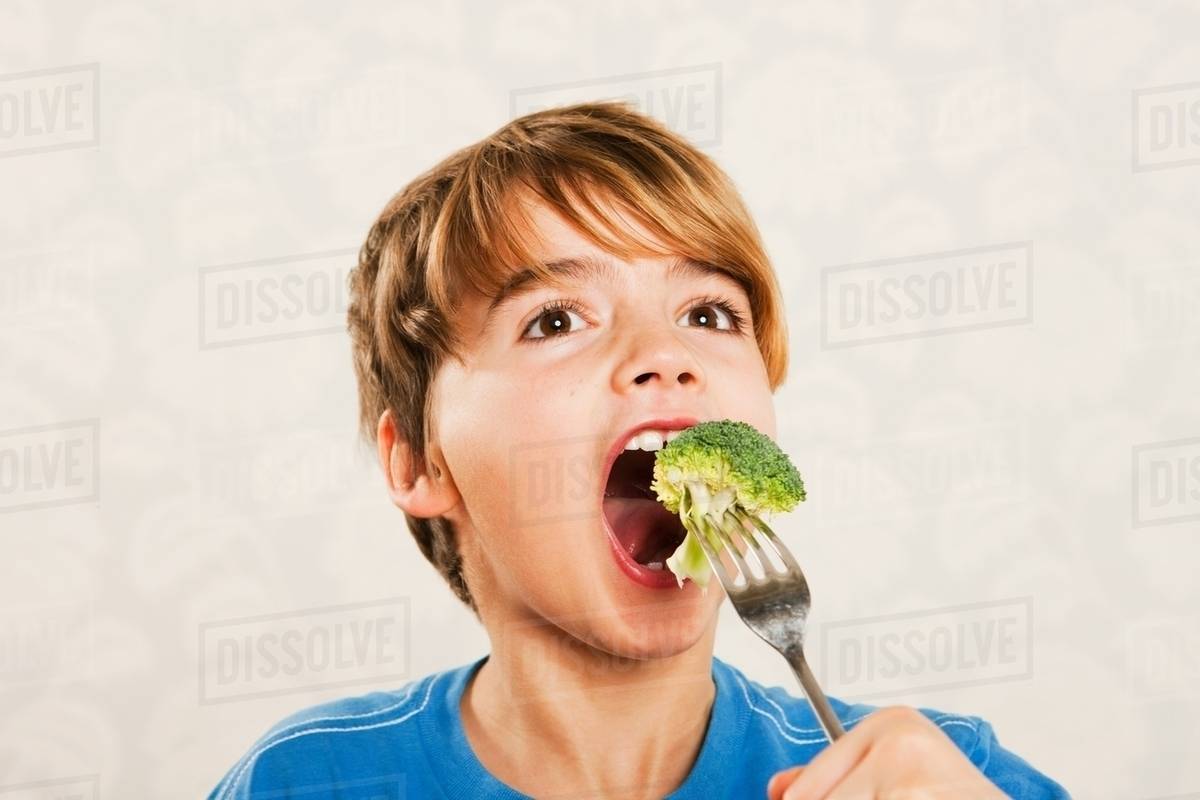 Boy eating broccoli Stock Photo Dissolve