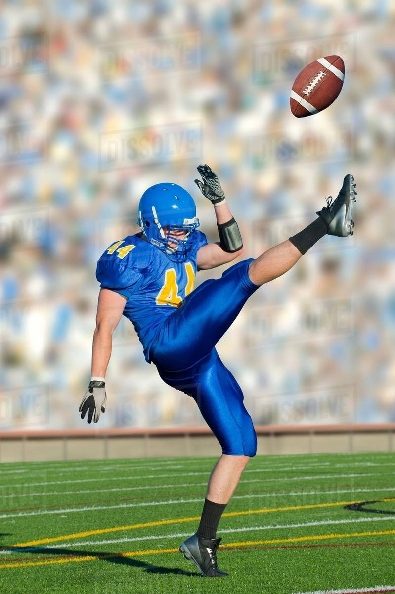 American footballer kicking ball Stock Photo Dissolve