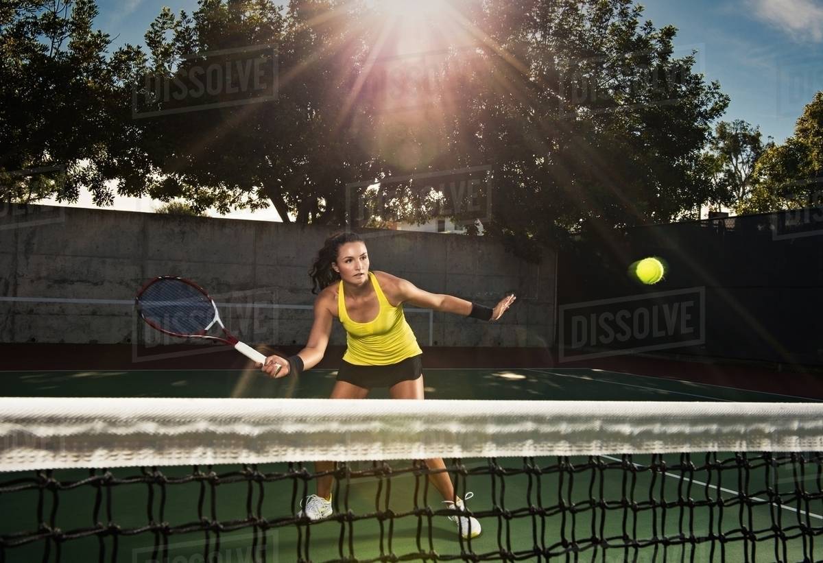 Female tennis player hitting ball over net Stock Photo Dissolve