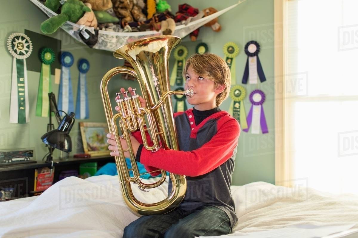 Boy playing tuba in bedroom Stock Photo Dissolve