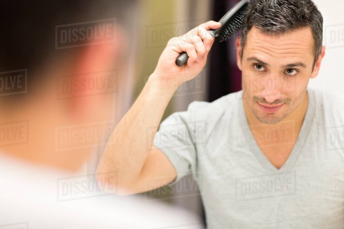 Mid Adult Man Looking In Mirror Brushing Hair Stock Photo