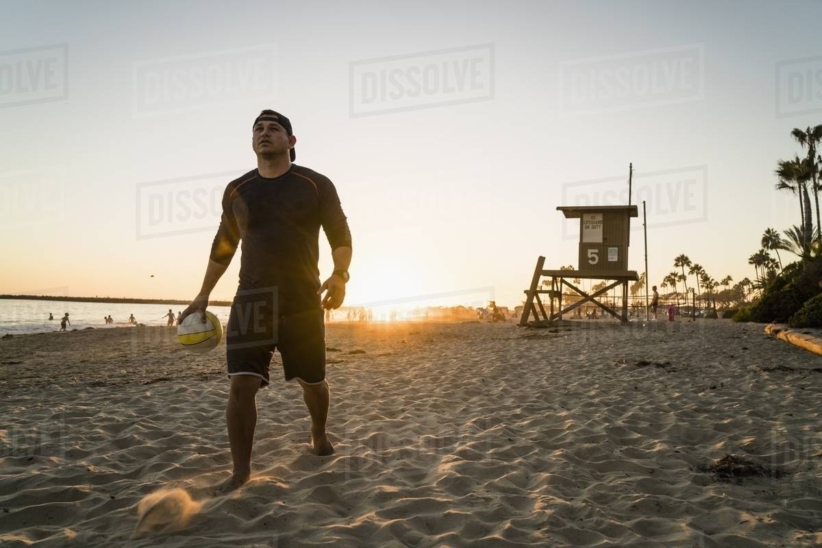 Young man playing beach volleyball at sunset, Newport Beach, California, USA Stock Photo