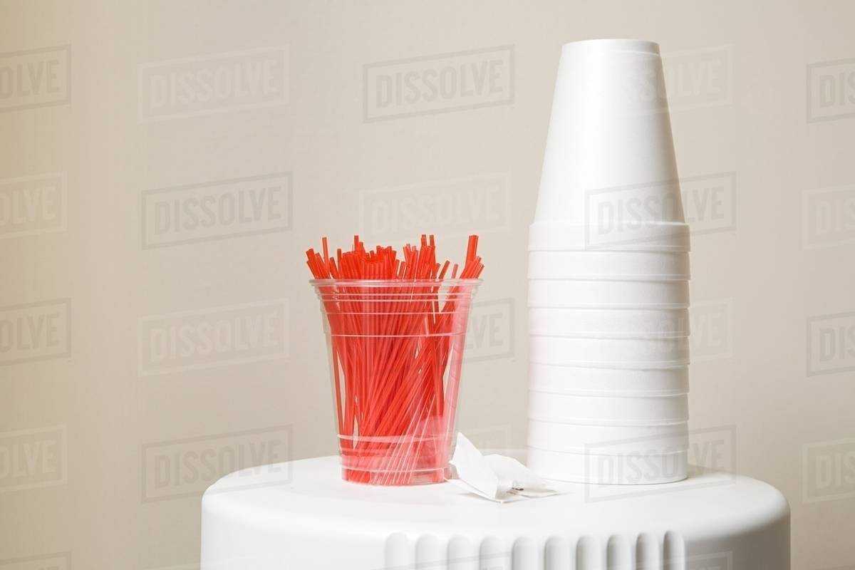 Polystyrene cups and plastic stirrers on top of coffee machine Stock