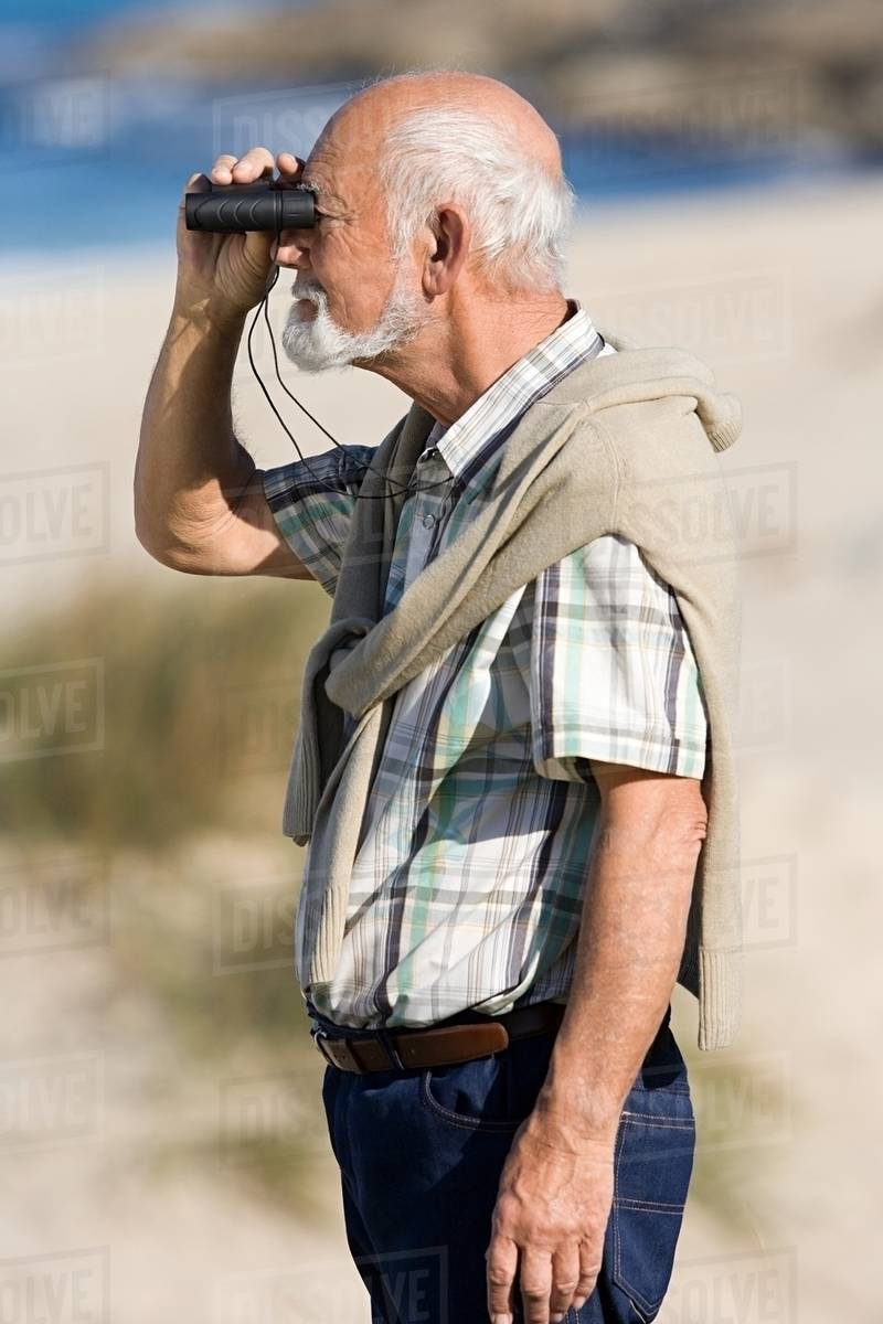 Senior man using binoculars Stock Photo Dissolve